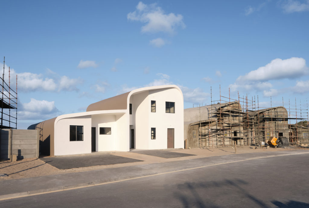 A newly finished Citra eHome stands beside two unfinished eHomes to its right.