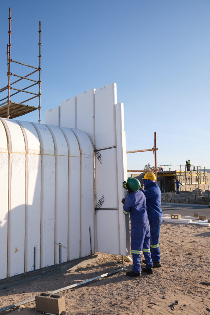 Two construction workers carefully holding and positioning a panel using Citra Building Technology, working to slot it into place on a house under construction.