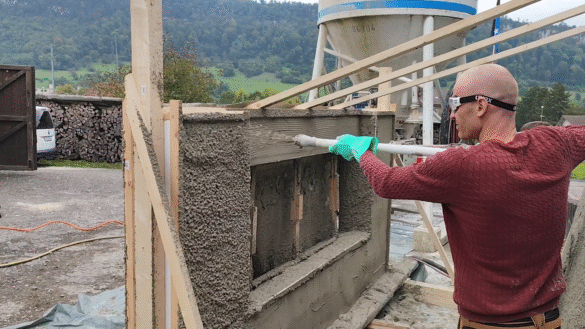 A Citra Building Technology wall mock-up, with a construction worker spraying plaster to the surface.