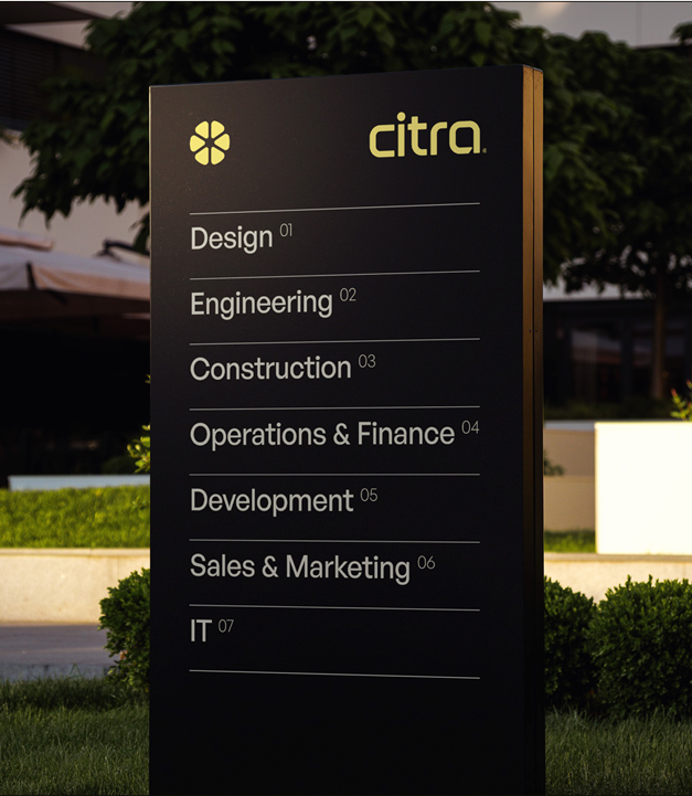A sleek black sign displaying the yellow Citra logo and emblem, listing company divisions: Design, Engineering, Construction, Operations & Finance, Development, Sales, & Marketing, and IT.