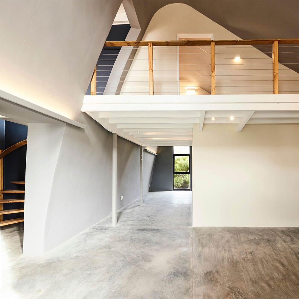 Open-plan modern interior with minimalist design and wooden balcony railing.