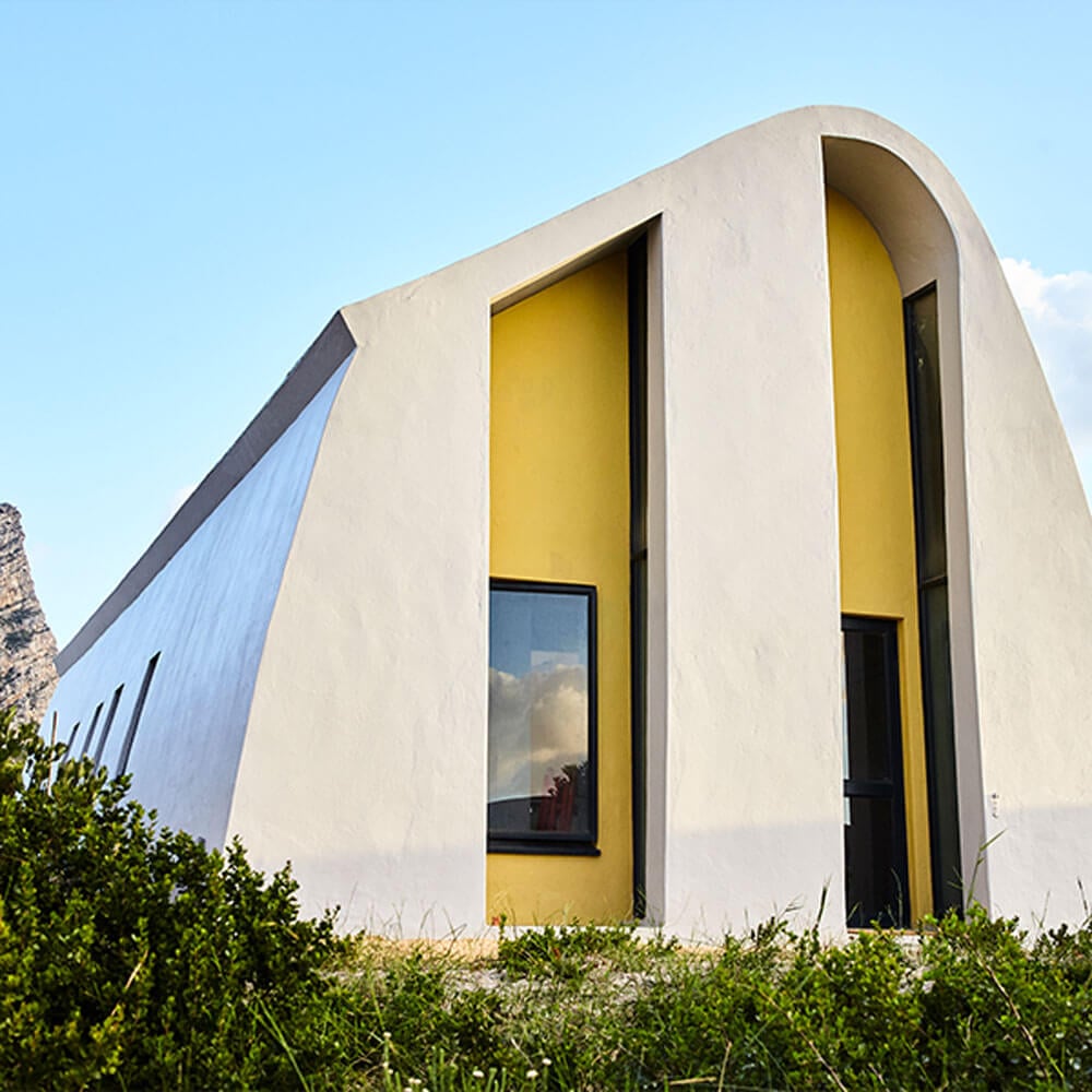 Contemporary white house with yellow accents and curved design, modern architecture in a natural set.