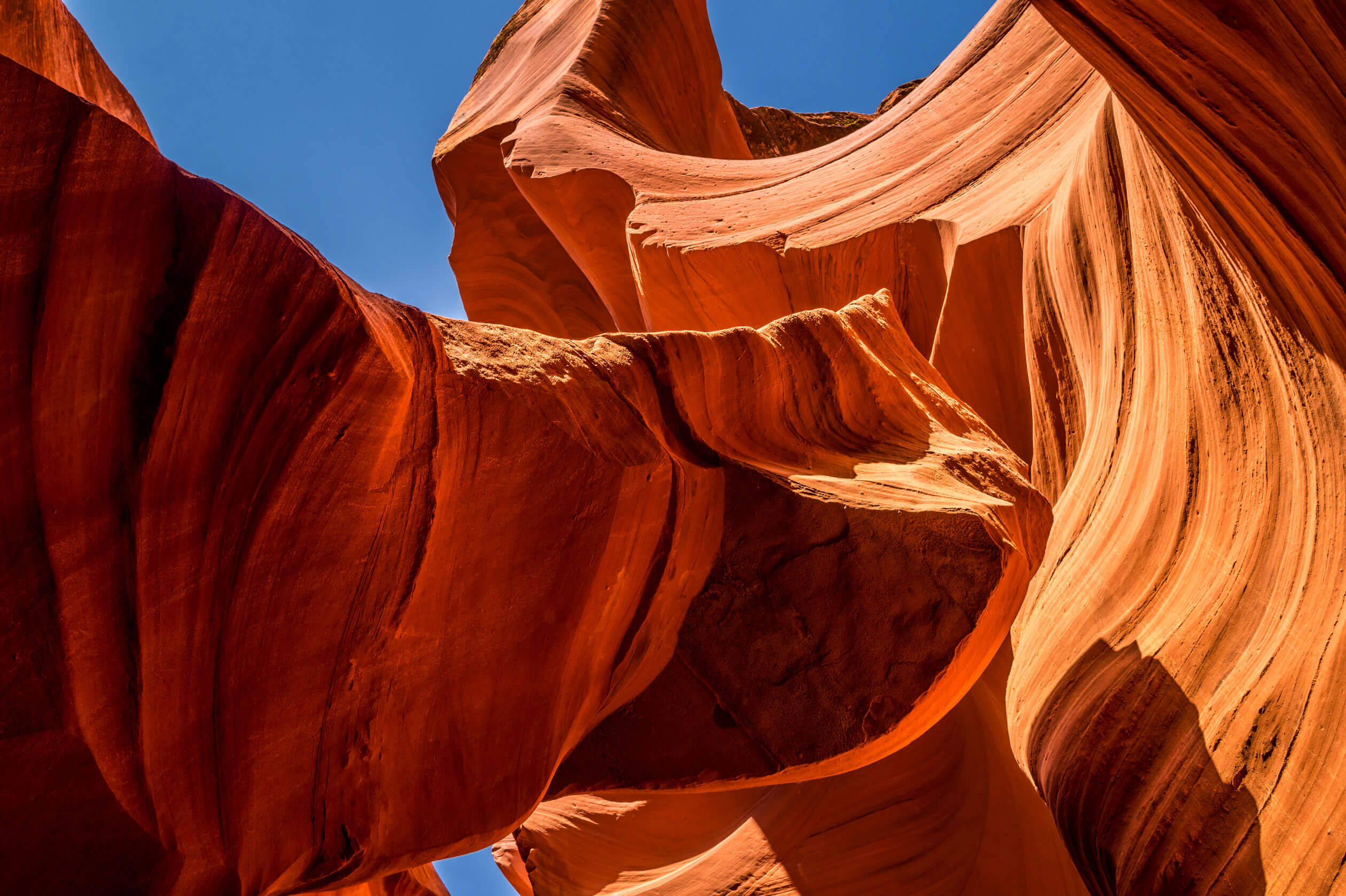 Design Philosophy Dramatic slot canyon with smooth, flowing sandstone formations under a clear blue sky.