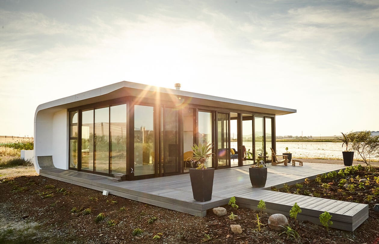 ePod Modern minimalist tiny house with large glass windows and outdoor deck in natural setting.