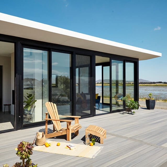 ePod Contemporary lakeside house featuring large glass sliding doors, outdoor seating, and scenic water v.