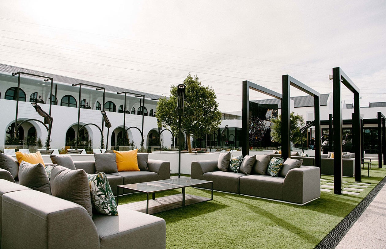Rooftop lounge area featuring contemporary outdoor sofas, lush greenery, and shaded pergolas for rel.