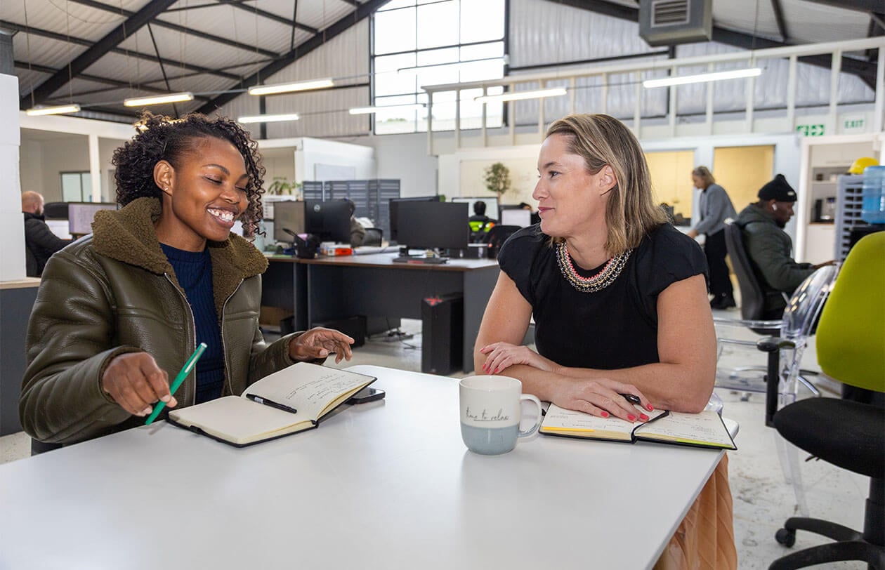Two women collaborating and discussing ideas in a contemporary office environment.