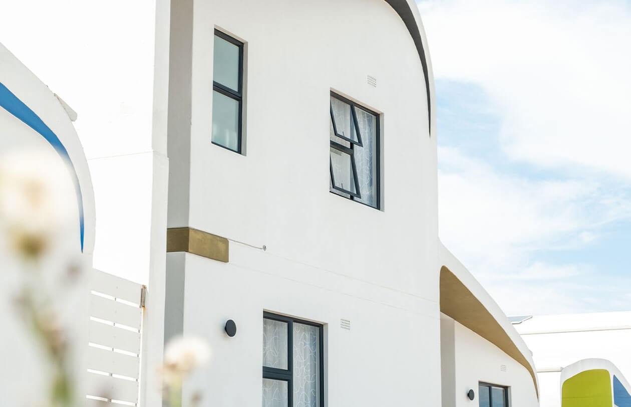 Modern white building with curved architecture and large windows in Citra development.