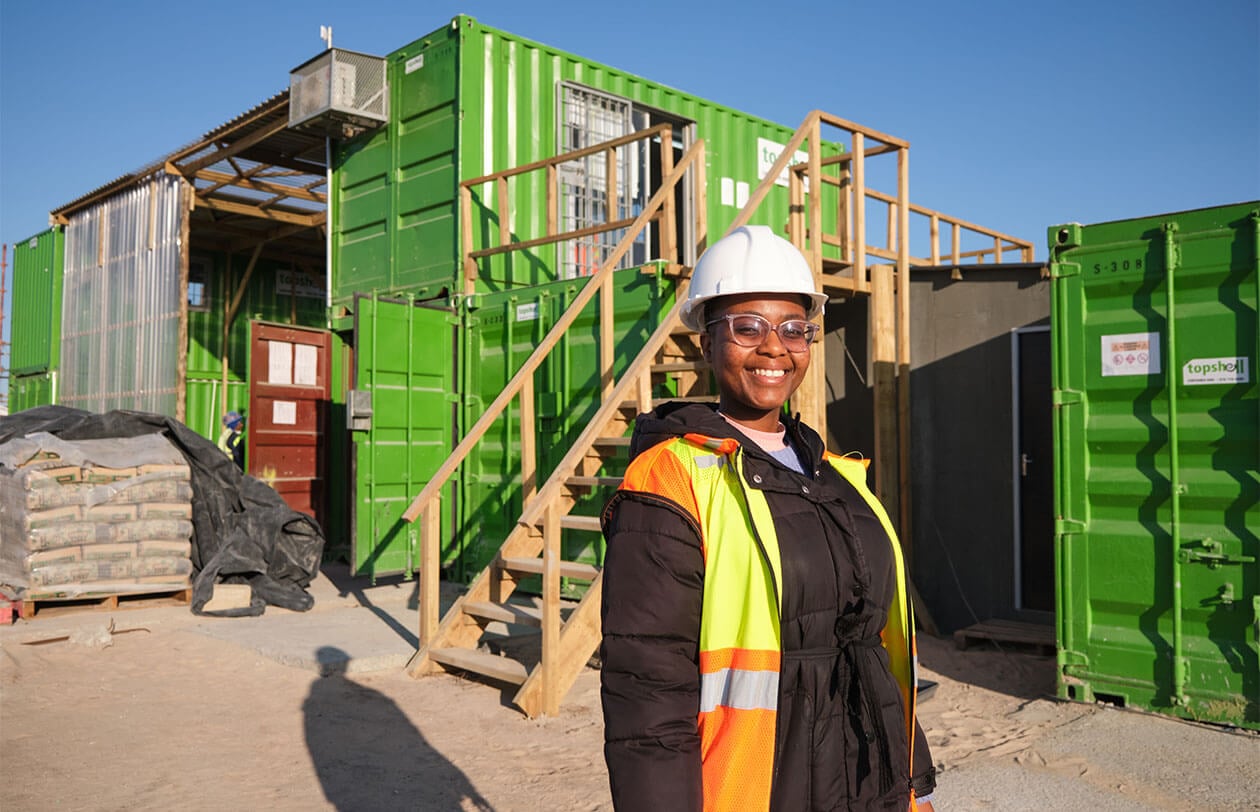 Female engineer in safety gear at Citra construction site with green shipping containers.