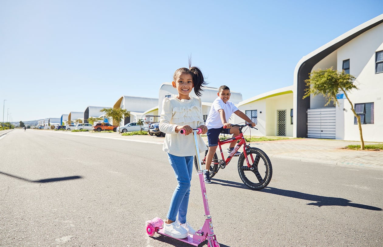 Riding scooters and cycling in a modern residential neighborhood with contemporary houses.