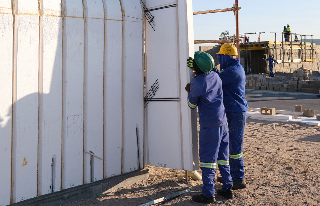 Deep Dive Construction workers installing insulated wall panels at a building site in South Africa.